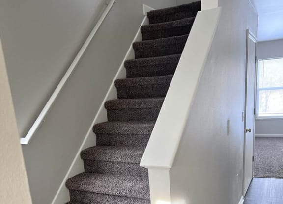 a carpeted staircase in a home with white walls at Mason Street Townhomes, Grand Rapids, 49505