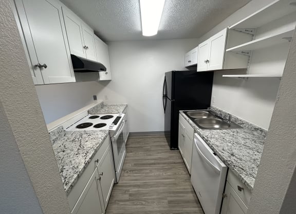 a kitchen with white cabinets and granite counter tops and a black refrigerator at Kings Court, Anchorage, 99501 ?