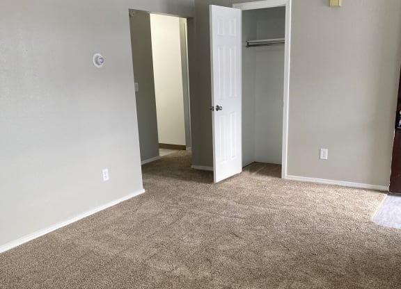 an empty living room with carpet and a door to a closet