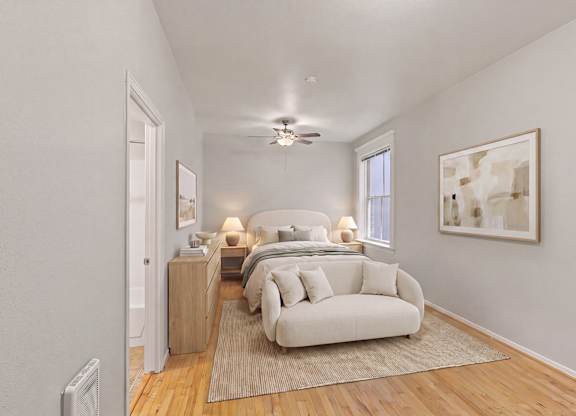 A bedroom with a bed, a couch, and a painting on the wall.