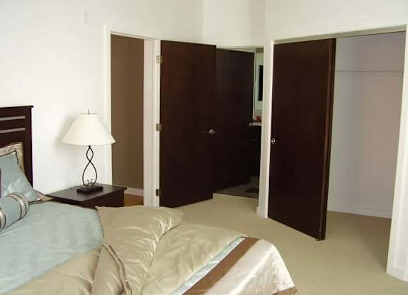 A bedroom with a bed, nightstand, and closet.