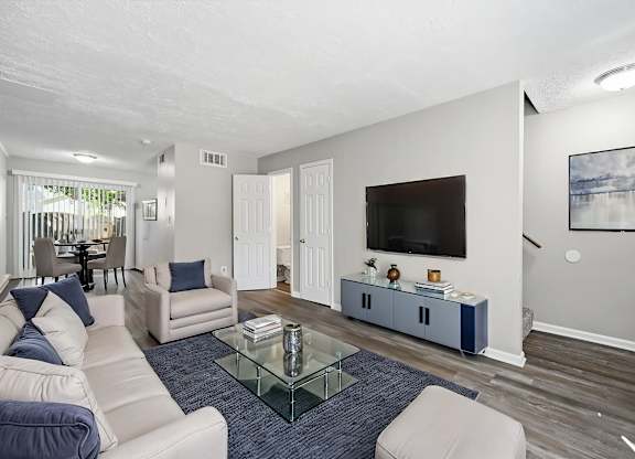 A living room with a glass coffee table and a white couch.
