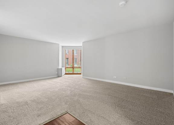 A room with a carpeted floor and a doorway leading to a balcony.