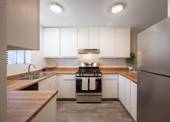 a kitchen with white cabinets and stainless steel appliances at Oak Park Apartments, Solvang, CA