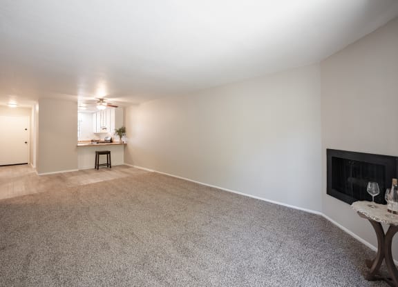an empty living room with a fireplace and a kitchen at Oak Park Apartments, Solvang, CA
