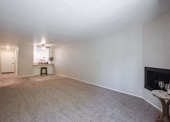 an empty living room with a fireplace and a kitchen  at Oak Park Apartments, California