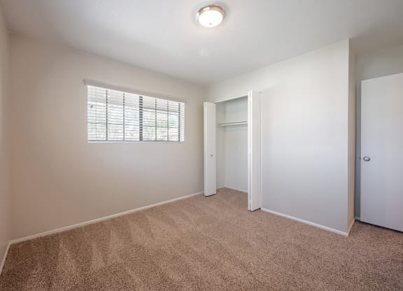 an empty bedroom with a window and a door to a closet  at Oak Park Apartments, California
