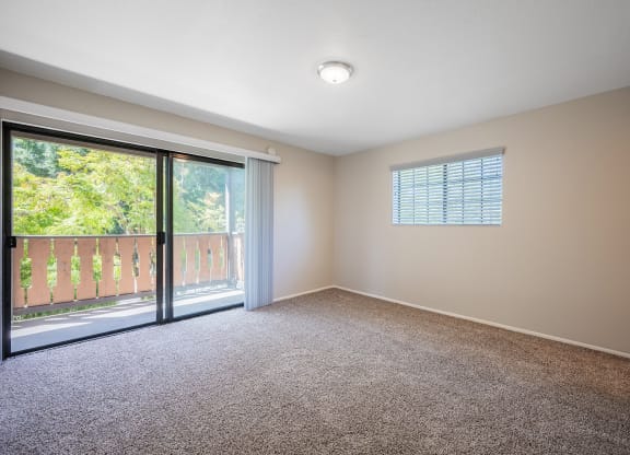 an empty living room with a sliding glass door to a balcony at Oak Park Apartments, Solvang, CA