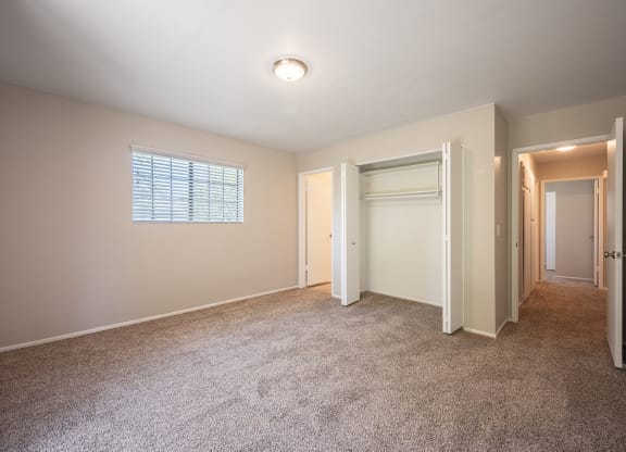 an empty bedroom with carpet and a door to a closet  at Oak Park Apartments, California, 93463