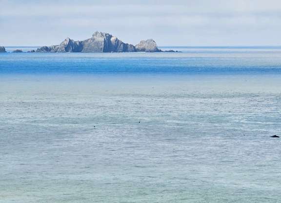 A small island is visible in the distance surrounded by the ocean.