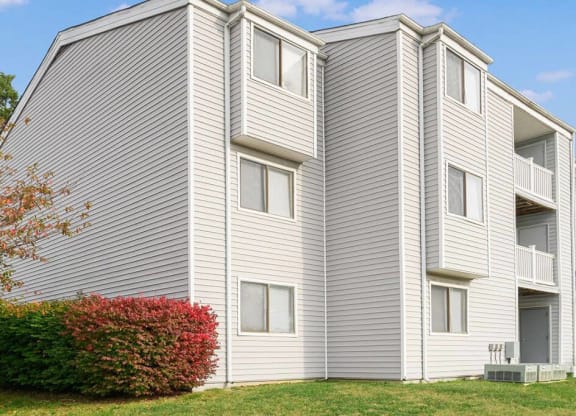 a white apartment building with a red shrub in front of it at ReNew Odenton, Maryland, 21113