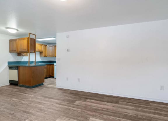 a living room with a white wall and a wooden floor  at ReNew End Street, Alaska