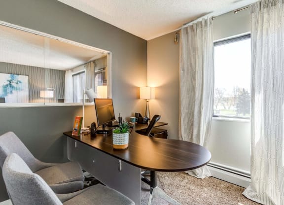 a desk with a computer and a chair in a room with a large window  at ReNew at Neill Lake, Eden Prairie