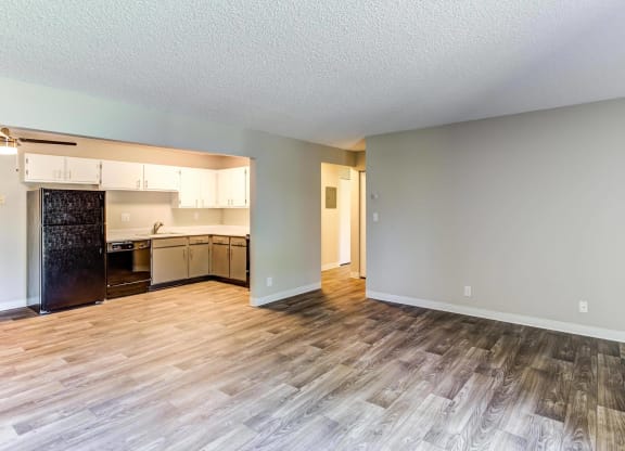 an empty living room with a kitchen in the background  at ReNew at Neill Lake, Eden Prairie