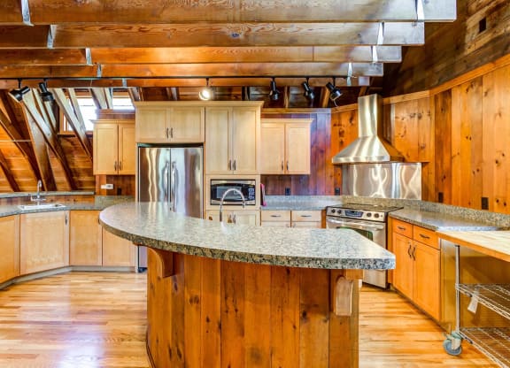 a kitchen with wooden cabinets and an island with granite countertops  at ReNew at Neill Lake, Minnesota, 55344