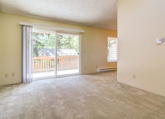 an empty living room with a sliding glass door and a balcony  at The Bluffs at Mountain Park, Oregon