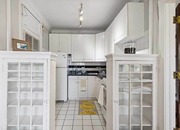a white kitchen with white cabinets and a yellow rug at The Bryant at Oak Park I & II, Oak Park