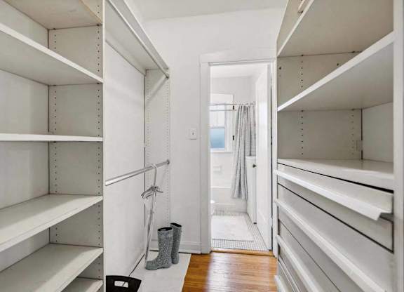 a large walk in closet with white shelves and a door at The Bryant at Oak Park I & II, Oak Park, 60302