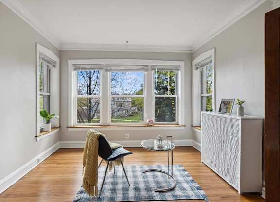 a living room with a chair and a table in front of a window at The Bryant at Oak Park I & II, Oak Park