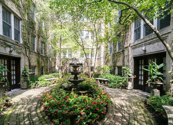 a courtyard with a fountain and flowers in front of a building at The Bryant at Oak Park I & II, Oak Park