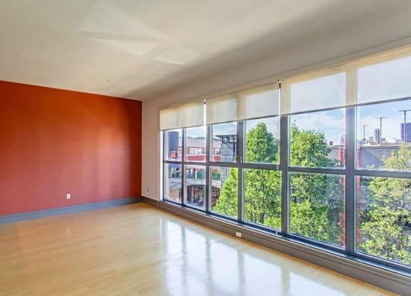 an empty room with a large window and hardwood floors at Flats at Southside, Pittsburgh Pennsylvania