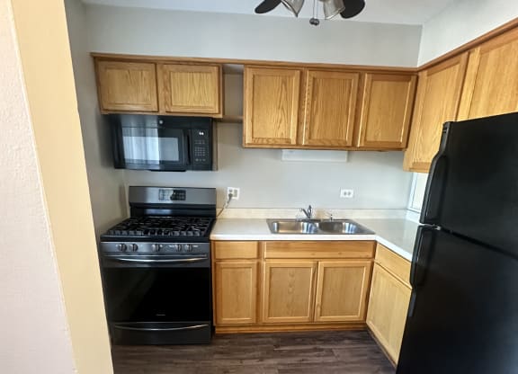 a kitchen with wooden cabinets and black appliances and a ceiling fan at River Oaks, North Aurora, Illinois