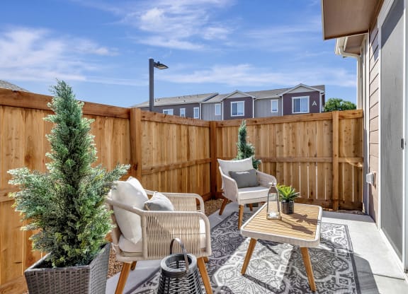 Patio with two chairs and a table and a fence