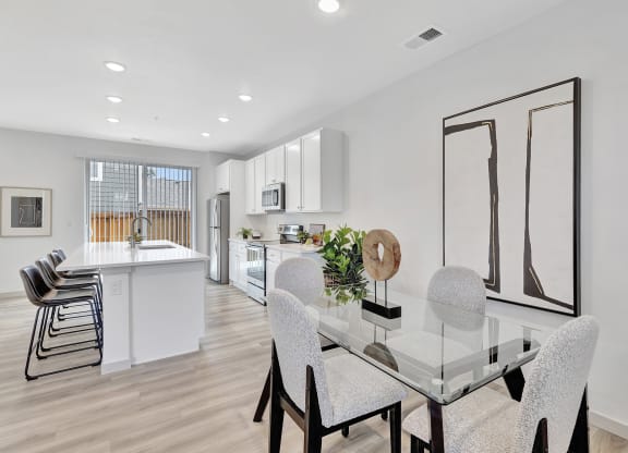 an open kitchen and dining room with a glass table and chairs