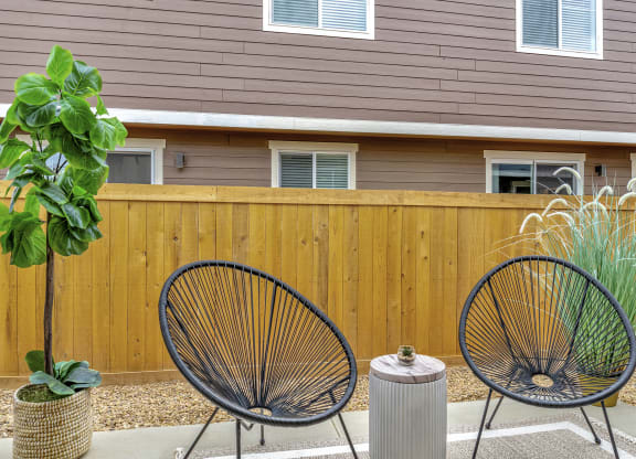 a patio with two chairs in front of a wooden fence