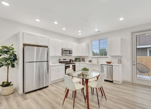 a white kitchen with a table and chairs and a refrigerator