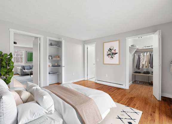 A bedroom with a bed, a couch, a wardrobe, and a plant.