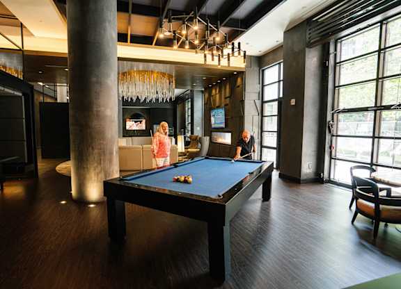 A woman is playing pool in a room with a pool table.