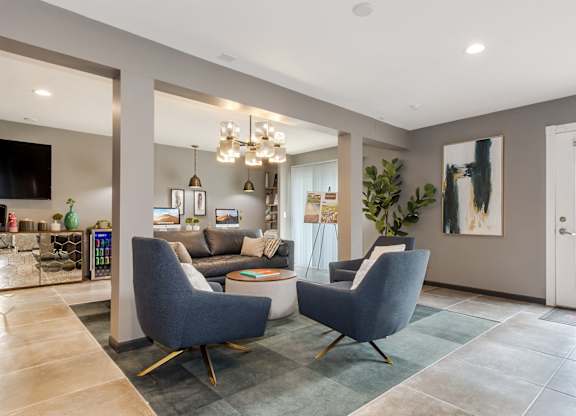 A modern living room with grey chairs and a grey sofa.
