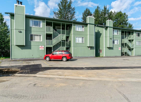 a green apartment building with a red car parked in front of it at ReNew Eagle River, Alaska
