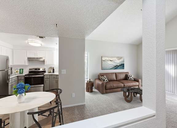 A kitchen with a table and chairs and a couch in the living room.