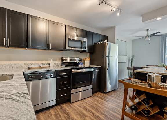 A modern kitchen with black cabinets and stainless steel appliances.at ReNew Wheaton Center, Wheaton Illinois