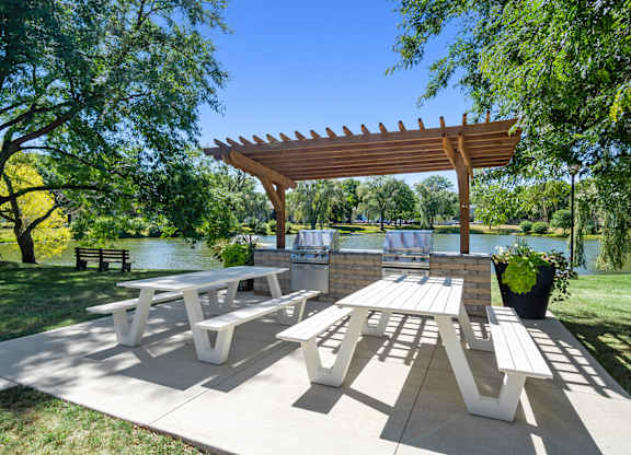 A wooden pergola shades a picnic table in a park.