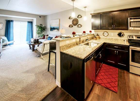 A kitchen with dark cabinets and view of the living room