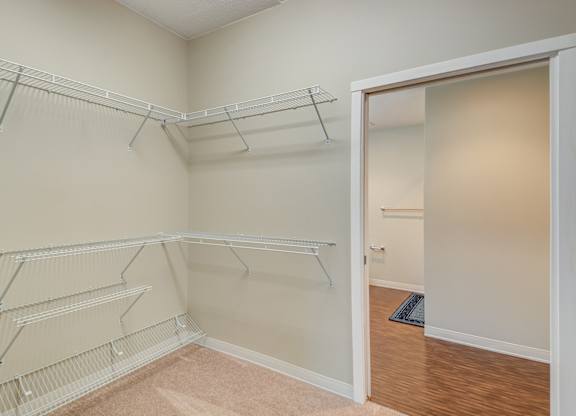 Empty room with white shelves and a doorway leading to another room.
