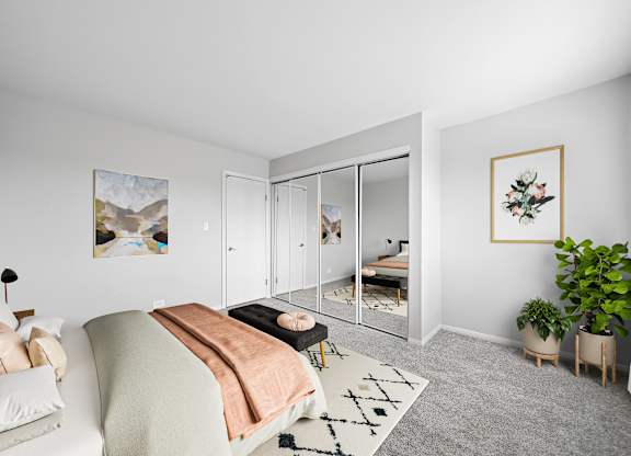 A bedroom with a bed, a couch, a rug, and a plant.