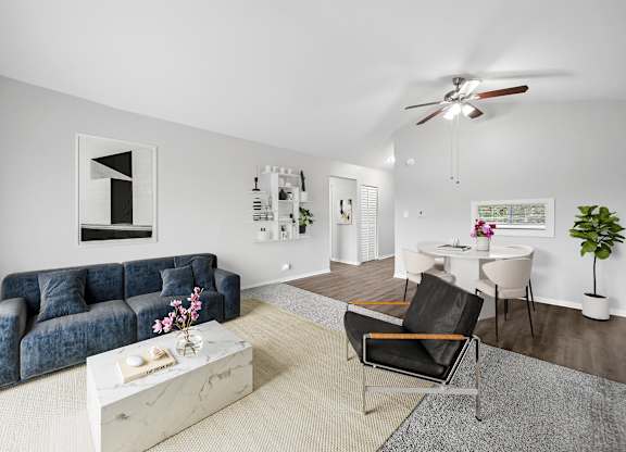A living room with a blue couch, a white coffee table, and a ceiling fan.