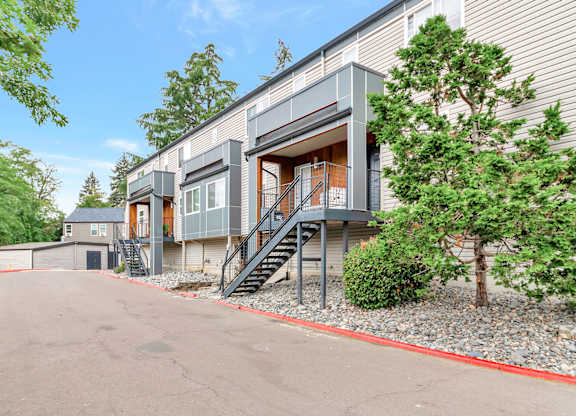 A modern two-story apartment with a grey exterior and a red border around the driveway at River Lofts Apartments, Tualatin, OR, 97062