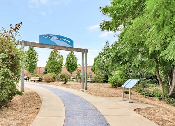 A sign for the Tualatin River Greenway is displayed above a walkway. at River Lofts Apartments, Tualatin, OR