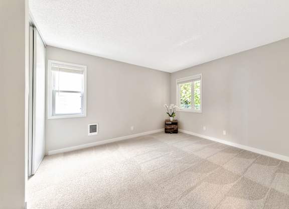 A room with a carpeted floor and two windows. at River Lofts Apartments, Tualatin, OR