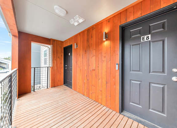 A black door with the number E8 on it is on the right side of a wooden wall. at River Lofts Apartments, Tualatin 97062
