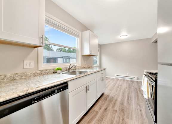 A kitchen with white cabinets and a marble countertop at River Lofts Apartments, Tualatin