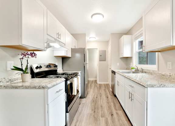 A kitchen with white cabinets and granite countertops. at River Lofts Apartments, Tualatin, Oregon