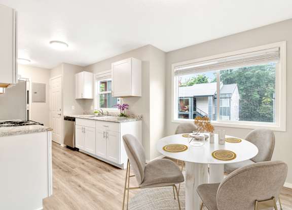 A kitchen with a table and chairs in front of a window.