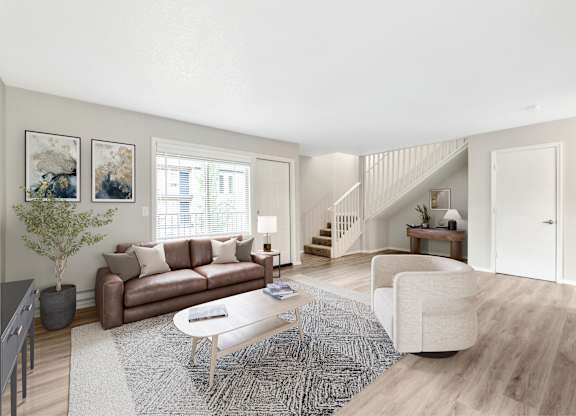 A living room with a brown couch, a white chair, and a coffee table.