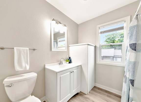 A white bathroom with a toilet, sink, and mirror. at River Lofts Apartments, Oregon